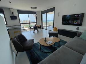 een woonkamer met een bank en een tafel bij #דירת יוקרה על הים Sunset Beach Apartment# in Giv‘at Olga