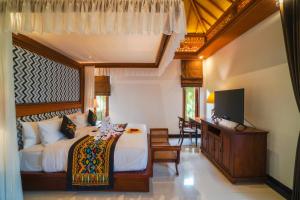 a bedroom with a bed and a flat screen tv at Giri Bhagawan Villas & Spa in Nusa Dua