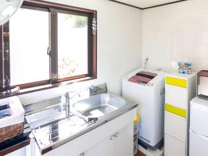a kitchen with a sink and a refrigerator at 国際通りと牧志駅まで徒歩5分 庭付き素敵な古民家 わらゆんSO 松武の古民家Traditional house in Naha