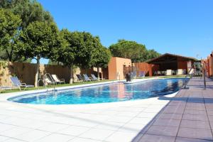 a swimming pool with chairs and trees and a building at Hostal Alhambra in Zahora