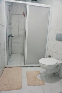 ein Badezimmer mit einer Dusche, einem WC und einem Teppich in der Unterkunft Geniş Bahçeli Barbekülü Kır Evi KOZALAK EVLERİ in Ortaca