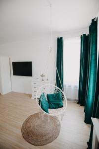 a hanging chair in a living room with green curtains at Studio Manzur in Braşov