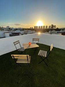 a table and chairs on a roof with the sunset at Atico duplex con Terraza en pleno centro de Jerez in Jerez de la Frontera