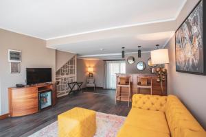 Orka Cove Hotel Penthouse & Suites Adults Only في فتحية: غرفة معيشة مع أريكة صفراء وتلفزيون