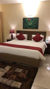a bedroom with a large bed with red pillows at The Neem in New Delhi