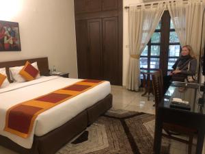 une femme debout dans une chambre d'hôtel avec un lit dans l'établissement The Neem, à New Delhi