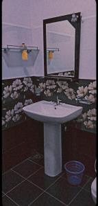a bathroom with a sink with a mirror and flowers at Lake Front Yala Safari in Kataragama
