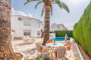a patio with a table and chairs and a palm tree at Spacious family home with Airco, private 5x10m pool, sandy beach 300m, free WiFi in Denia