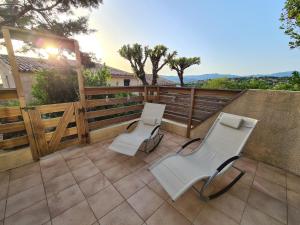 eine Terrasse mit zwei weißen Stühlen und einem Zaun in der Unterkunft Studio avec terasse vue mer in Porticcio