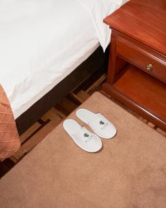 - une paire de chaussons blancs à l'étage, à côté d'un lit dans l'établissement El Tumi Hotel, à Huaraz