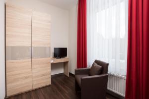 Zimmer mit einem Stuhl, einem TV und roten Vorhängen in der Unterkunft Hotel Südlohner Hof - Ristorante Da Fabio in Südlohn
