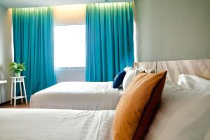 a bedroom with two beds and a window with blue curtains at G5 HOTEL AND SERVICED APARTMENT in Johor Bahru