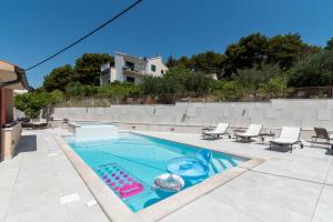 a swimming pool with chaise lounges and chairs in a backyard at Villa Lavandula with heated swimming pool in Trogir