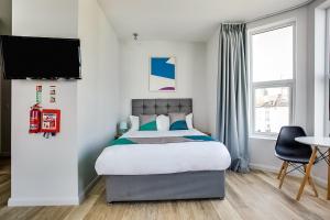 a bedroom with a bed and a tv on a wall at OYO Studiotel GY - Modern Hotel Apartments in Great Yarmouth