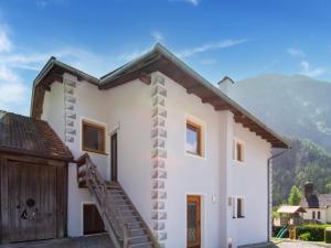 a white house with a wooden door and mountains in the background at Cozy Holiday Home in Tyrol near Ski Area in Oetz