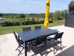 einem schwarzen Tisch mit Stühlen und einem Sonnenschirm in der Unterkunft Gite du chêne vert - Périgord in Salignac Eyvigues