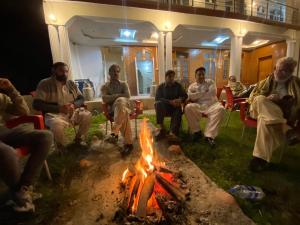 a group of people sitting around a fire at Relax Cottages & Resort Kalam in Kalām