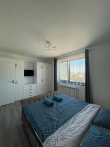 a bedroom with a bed with blue sheets and a window at LS Lake Apartment Mamaia Nord in Mamaia Sat/Năvodari