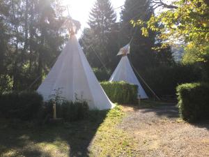 dwa białe namioty w ogrodzie z drzewami w obiekcie Arkeo - Luxury tents and cabins at the river w mieście Nonceveux