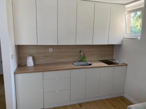 a kitchen with white cabinets and a sink at Mia apartman Visoko in Visoko +7 photos
