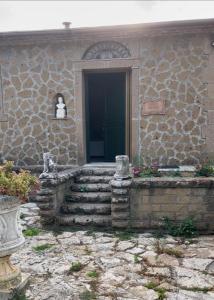 un edificio de piedra con una puerta y escaleras delante en Casa Romano, en Manciano