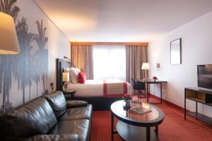 a hotel room with a bed and a couch at Le M & Spa Bordeaux Aéroport by Hôtels & Préférence in Mérignac