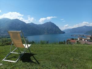 a chair sitting on top of a field with a lake at Villa Domus Bianca Mountain Lake Iseo Hospitality in Costa Volpino