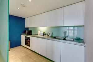 uma cozinha com armários brancos e uma parede azul em 2 Bed- Pureserviced 5 Brewhouse em Plymouth