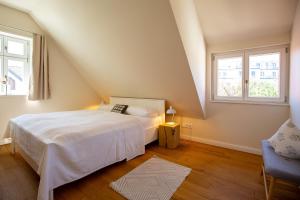 a bedroom with a white bed and two windows at Kapitänshaus Luv & Lee in Wustrow