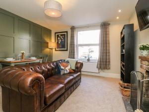 a living room with a brown leather couch and a window at Fonaby in Market Rasen