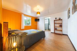 a bedroom with a bed and an orange wall at Kaz Noulafé in Saint-Leu