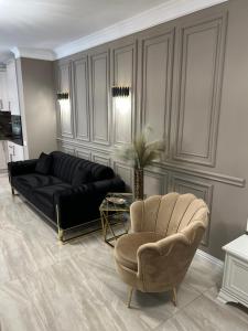 een woonkamer met een zwarte bank en een stoel bij Golden Apartment in Oradea