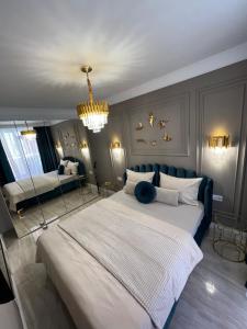 a large bedroom with a large bed and a chandelier at Golden Apartment in Oradea