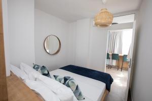 een witte slaapkamer met een bed en een spiegel bij Vera's Lapad suite in Dubrovnik