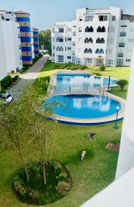 a large swimming pool in front of some buildings at TANGER/ASILAH: APPART 50m2 FACE MER ET PISCINES, 5 PLACES, TOUT ÉQUIPÉ+WIFI+CLIM in Briech