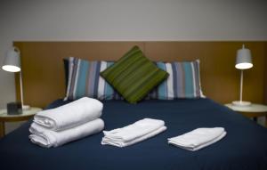 a blue bed with towels on it with two lamps at Darwin City Suites with Harbour View in Darwin