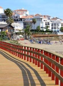 een rood hek op een promenade bij het strand bij Estudio con encanto a metros de la playa in Sitio de Calahonda