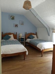 2 camas en una habitación con paredes azules en Ti Dour, en Pluméliau