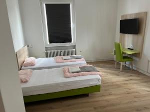 two beds in a room with a desk and a window at Waffel Cafe HOSTEL Monteurwohnung Ferienwohnung in Kassel