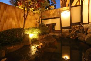 une arrière-cour de nuit avec des lumières sur une clôture dans l'établissement 野沢温泉　奈良屋旅館, à Nozawa Onsen