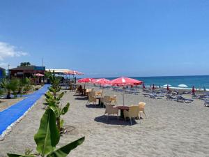 a beach with chairs and tables and red umbrellas at BIN BILLA HOTEL in Alanya