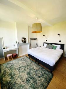 a bedroom with a bed and a desk and a rug at Huisje aan de Schelde in Spiere