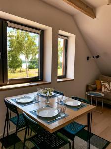 a dining room table with chairs and a large window at Apartamenty KAHOY balia pomost Kozin in Kozin