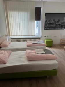 a room with three beds with pink towels on them at Waffel Cafe HOSTEL Monteurwohnung Ferienwohnung in Kassel