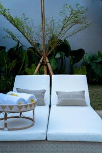 2 camas blancas con almohadas y mesa en Casa Benita By Bracha Villas Management, en Seminyak