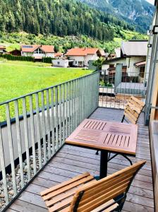 una terraza de madera con 2 sillas y una mesa en Arlberg Mountain Resort, en Pettneu am Arlberg