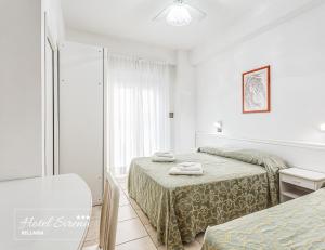 um quarto branco com 2 camas e um espelho em Hotel Sirena em Bellaria-Igea Marina
