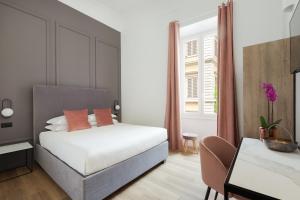 um quarto com uma cama, uma secretária e uma janela em DA ME Suites em Roma