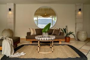 a living room with a couch and a round mirror at Casa Benita By Bracha Villas Management in Seminyak