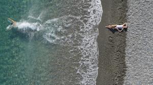 twee mensen liggend op het strand naast de oceaan bij Asterion Suites & Spa - Designed for Adults in Gerani Chanion